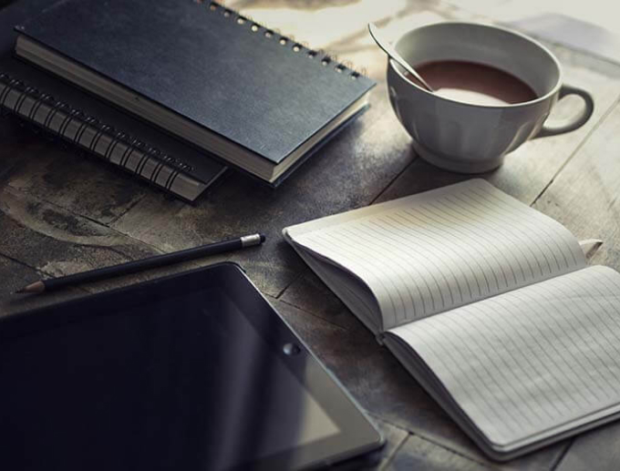 a notebook, a cup of coffee and a tablet